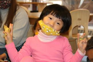 A little girl in child care with a SpongeBob SquarePants mask on her face and a pink shirt poses for the camera