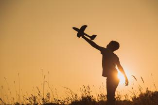 kids silhouette playing with airplane toy 