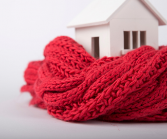 A white scale model house heated by a red scarf.