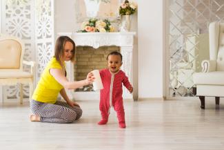 A mother and baby play together on the floor of their house. 