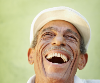 The face of an older man laughing with his mouth open.