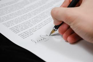 The hand of a person who is signing a document. 